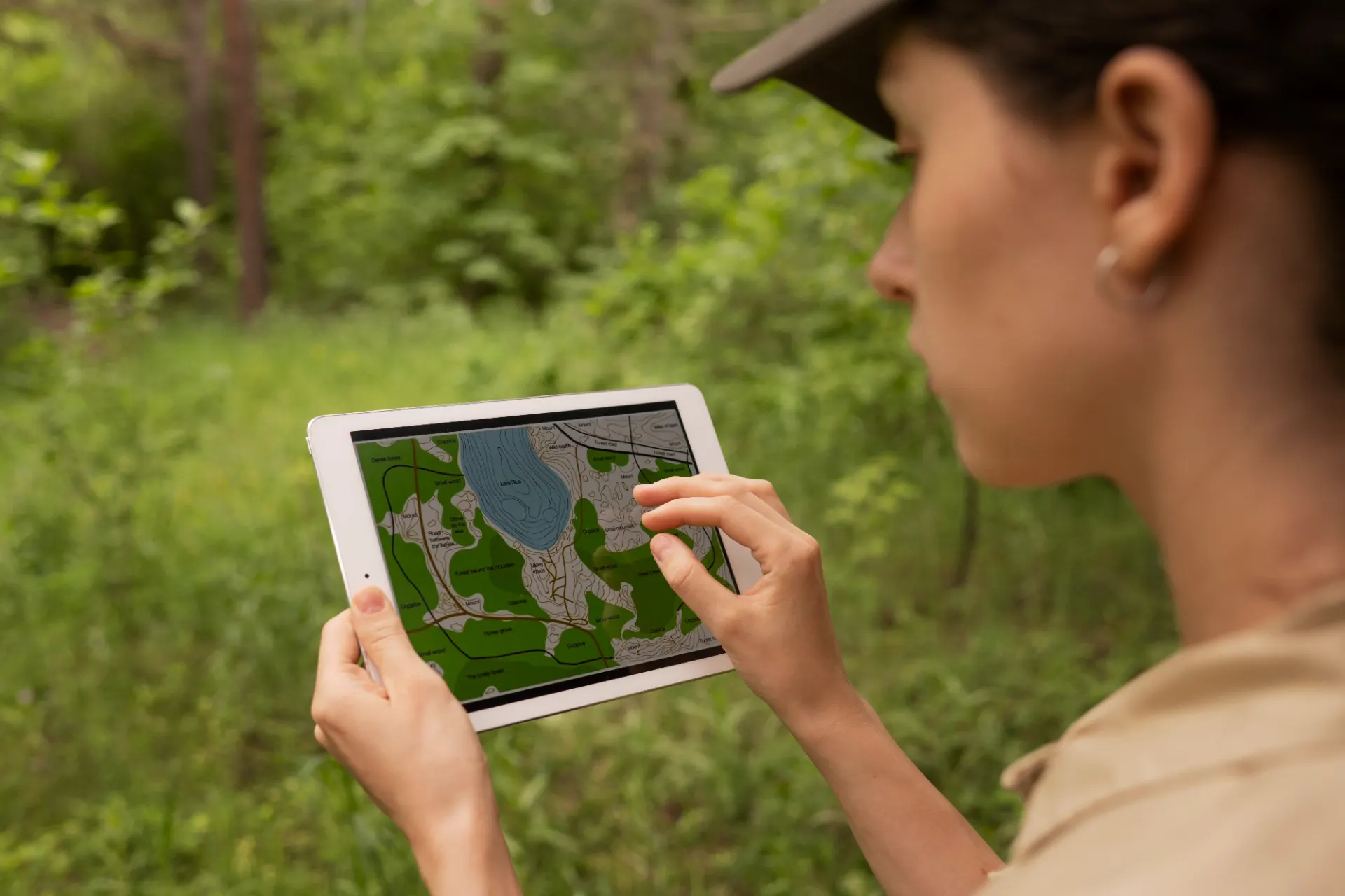 Pessoa observa um mapa em um tablet ao ar livre, usando informações geográficas para planejar um trajeto, destacando a importação e impacto ambiental de decisões mais conscientes.